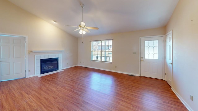 unfurnished living room with a tile fireplace, wood-type flooring, lofted ceiling, and ceiling fan