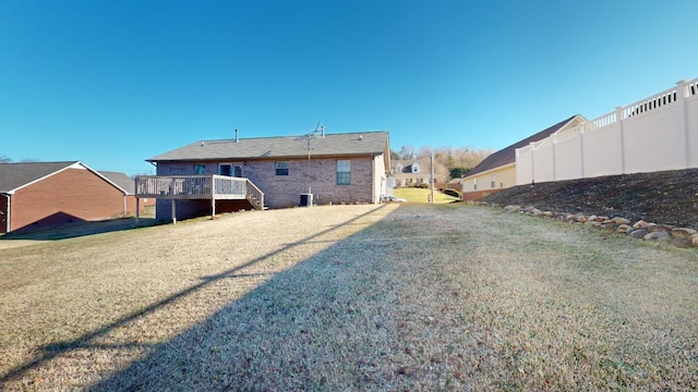 rear view of property with central AC unit, a yard, and a deck