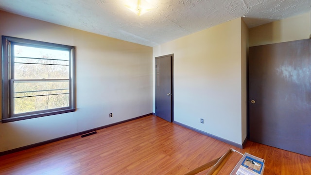 empty room with hardwood / wood-style floors and a textured ceiling