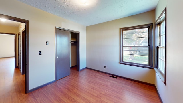 unfurnished bedroom with a closet, a textured ceiling, and hardwood / wood-style flooring