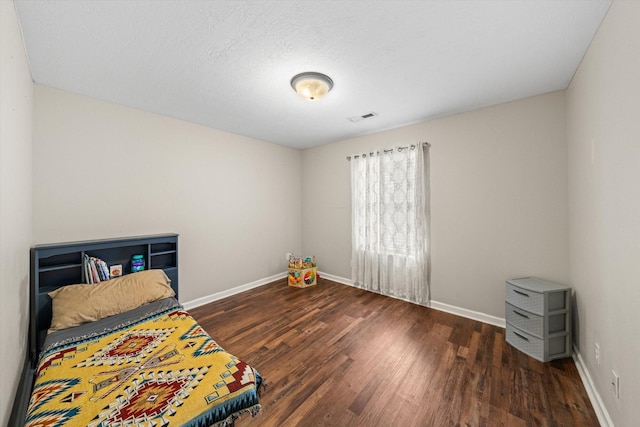 bedroom featuring visible vents, baseboards, and wood finished floors