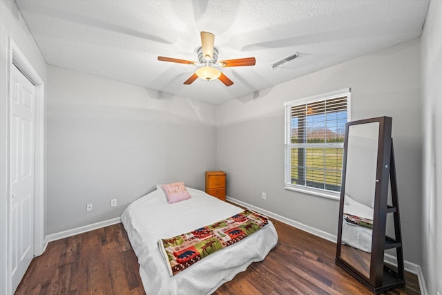 bedroom with a ceiling fan, wood finished floors, visible vents, and baseboards