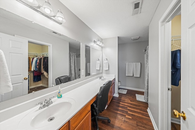 bathroom with toilet, wood finished floors, a sink, visible vents, and baseboards