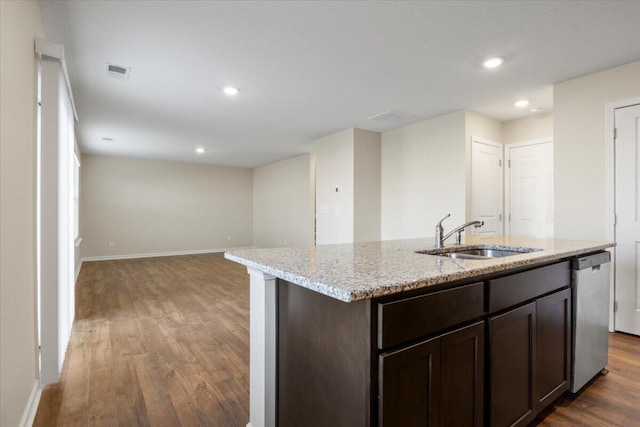 kitchen with dishwasher, an island with sink, sink, dark hardwood / wood-style flooring, and light stone counters