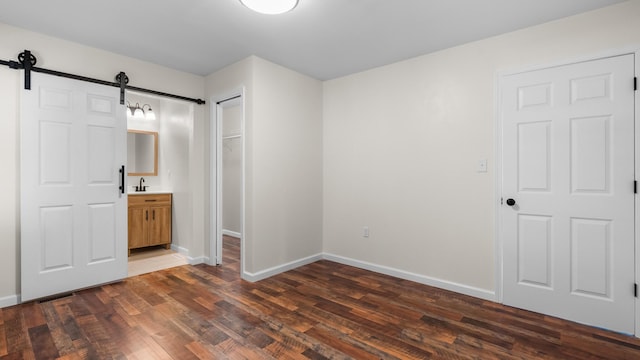 1302 Chestnut St, Kingsport, TN 37664 - unfurnished bedroom with a barn door, a sink, dark wood-style floors, baseboards, and connected bathroom