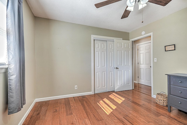 unfurnished bedroom featuring ceiling fan, a textured ceiling, light hardwood / wood-style floors, and a closet