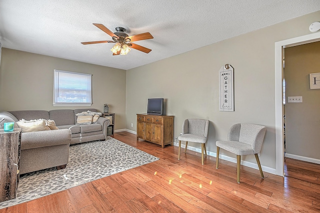 living room with ceiling fan, light hardwood / wood-style floors, and a textured ceiling