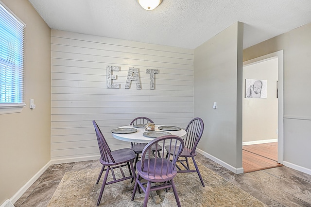 dining room featuring a textured ceiling and wood walls