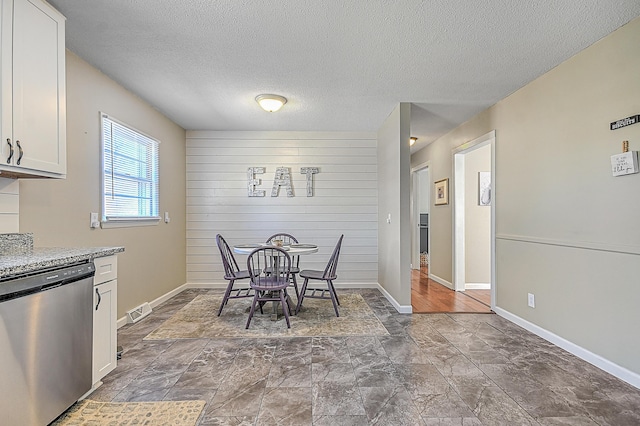 dining room featuring a textured ceiling and wooden walls