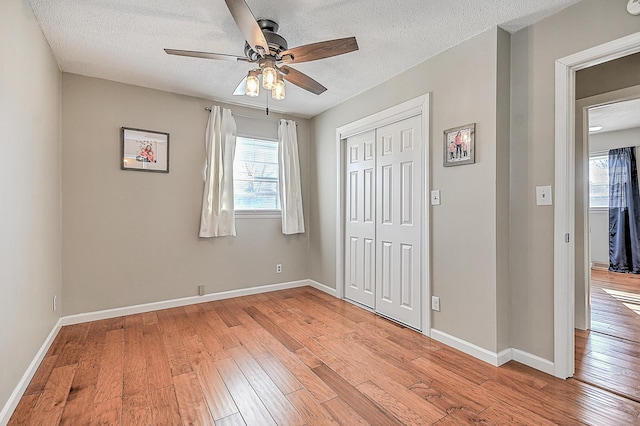 unfurnished bedroom with ceiling fan, light hardwood / wood-style floors, a closet, and a textured ceiling