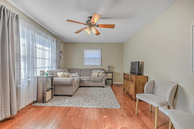 living room featuring a textured ceiling, ceiling fan, and light wood-type flooring