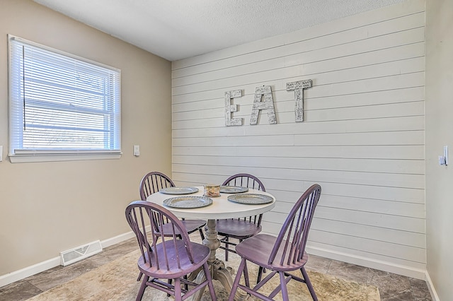 dining space with a textured ceiling and wood walls