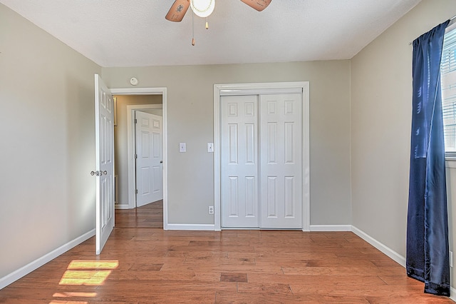 unfurnished bedroom with ceiling fan, a closet, a textured ceiling, and light wood-type flooring