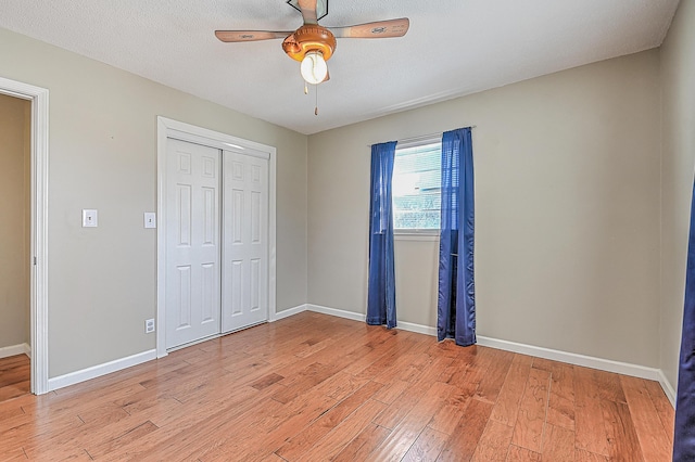 unfurnished bedroom featuring ceiling fan, light hardwood / wood-style floors, a closet, and a textured ceiling