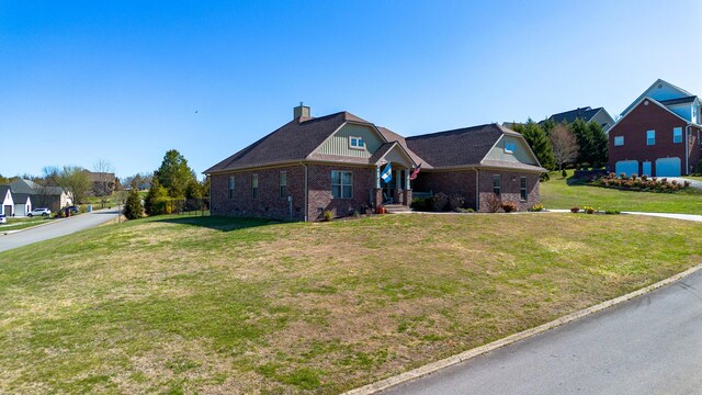 view of front of property with brick siding, a chimney, a front yard, and a residential view