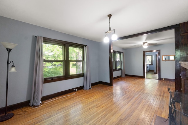 spare room featuring light wood-type flooring, baseboards, ceiling fan, and a healthy amount of sunlight