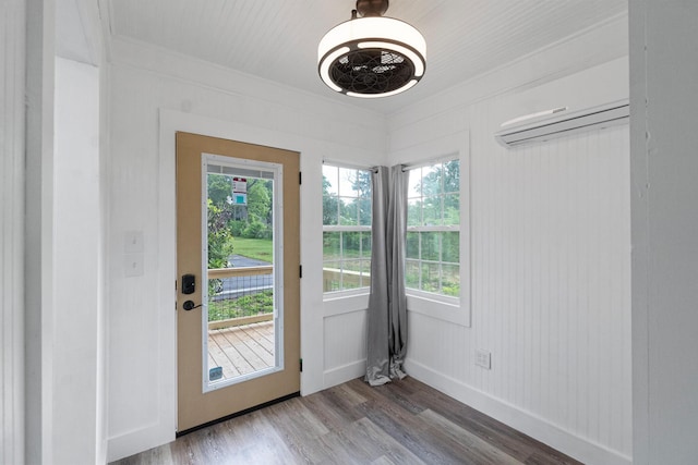 doorway to outside featuring crown molding, baseboards, a healthy amount of sunlight, and wood finished floors