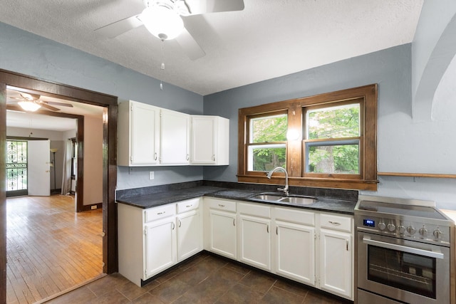 kitchen featuring a sink, a wealth of natural light, white cabinetry, and electric stove