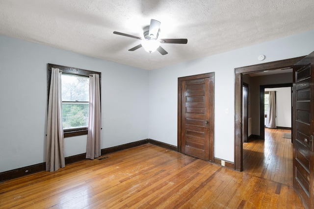 unfurnished bedroom featuring a textured ceiling, baseboards, visible vents, and light wood-type flooring