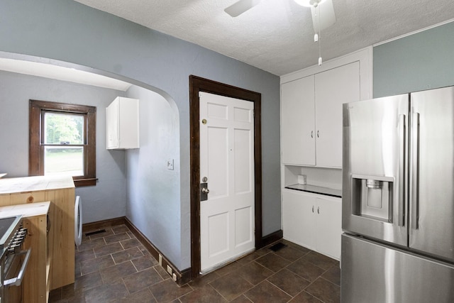 kitchen with arched walkways, white cabinets, baseboards, and stainless steel refrigerator with ice dispenser