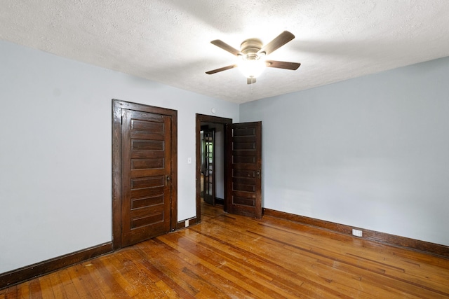 unfurnished bedroom with baseboards, ceiling fan, a textured ceiling, and hardwood / wood-style floors
