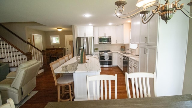976 Bridgeview Hills Dr, Dandridge, TN 37725 - kitchen with stainless steel appliances, a kitchen bar, decorative backsplash, white cabinets, and a kitchen island