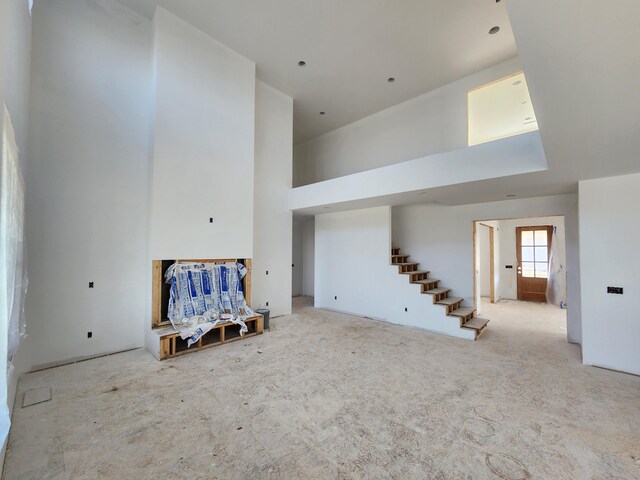 unfurnished living room featuring a towering ceiling