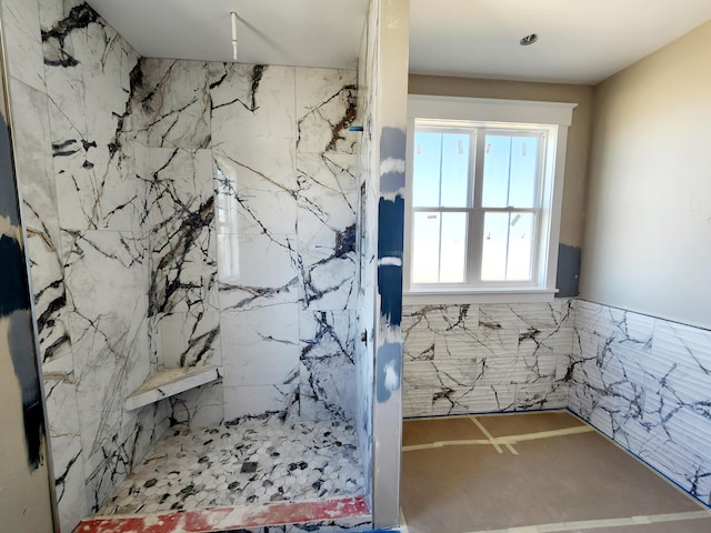 bathroom with a marble finish shower and tile walls