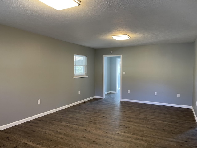 empty room with dark hardwood / wood-style floors and a textured ceiling