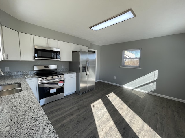 kitchen with white cabinetry, sink, dark wood-type flooring, stainless steel appliances, and light stone counters