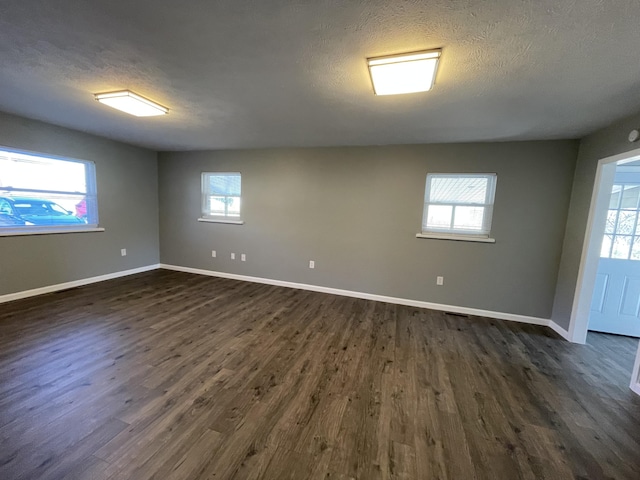 empty room with dark hardwood / wood-style flooring and a textured ceiling