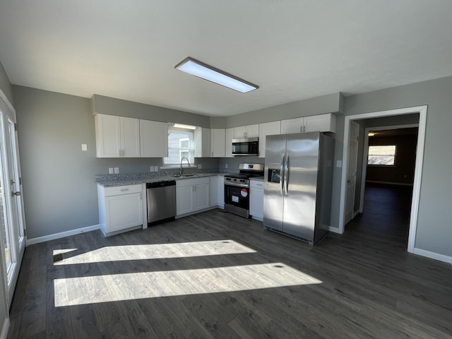 kitchen featuring white cabinetry, sink, light stone counters, dark hardwood / wood-style floors, and appliances with stainless steel finishes