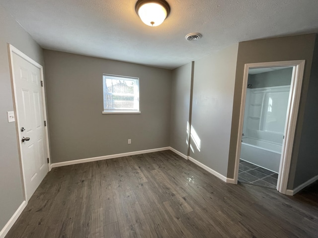 spare room with a textured ceiling and dark hardwood / wood-style floors