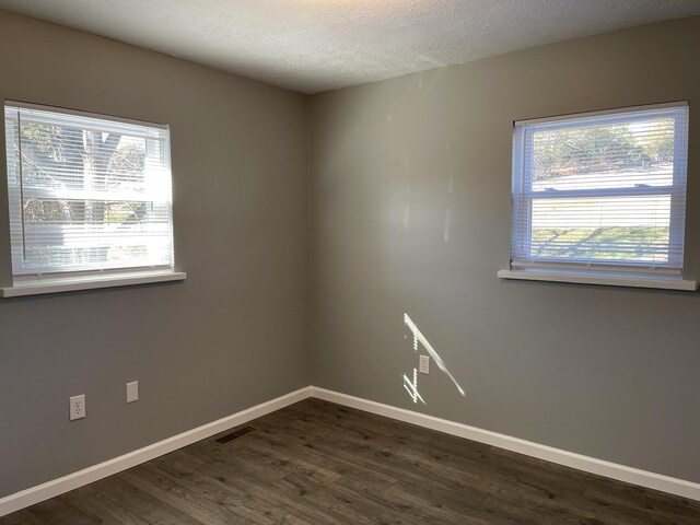 spare room with a textured ceiling and dark wood-type flooring