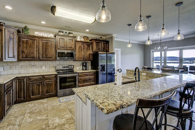 kitchen with hanging light fixtures, a kitchen breakfast bar, a large island with sink, and appliances with stainless steel finishes