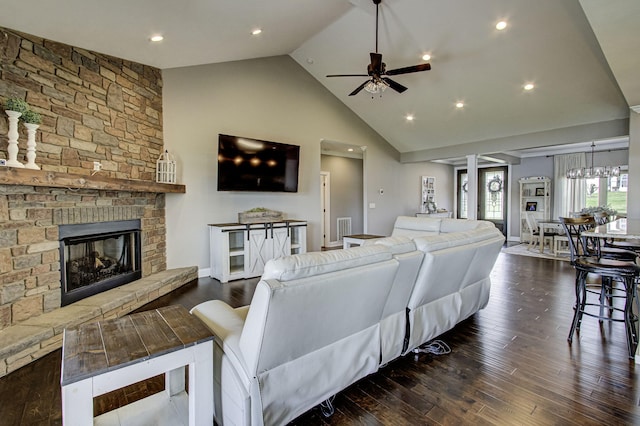 living room featuring dark hardwood / wood-style floors, ceiling fan, a stone fireplace, and high vaulted ceiling