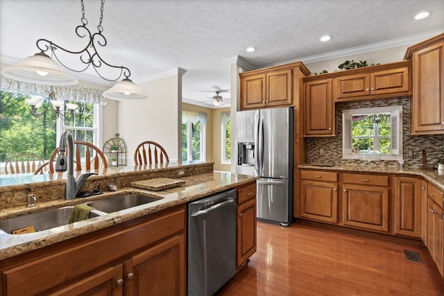 4018 Eagles Nest Dr, Morristown, TN 37813 - kitchen with stainless steel appliances, a sink, brown cabinetry, crown molding, and decorative light fixtures
