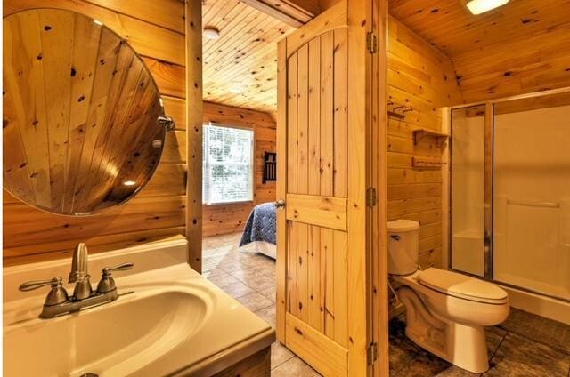 bathroom featuring sink, wooden walls, wooden ceiling, and toilet