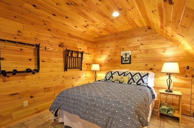 bedroom with vaulted ceiling, light tile patterned flooring, wood ceiling, and wood walls