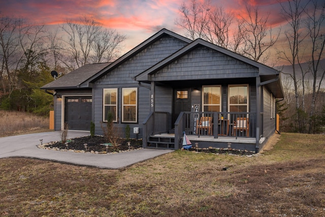 view of front of property with a porch, a garage, and a yard