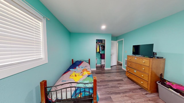 bedroom featuring a closet, light hardwood / wood-style floors, and multiple windows