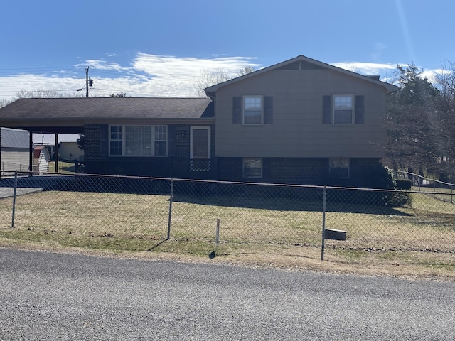 split level home featuring a fenced front yard, a front yard, and brick siding