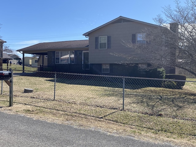 split level home featuring a fenced front yard, a front yard, and brick siding