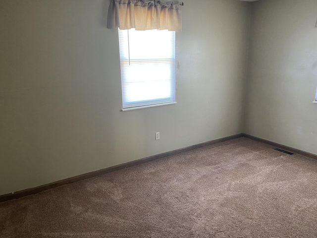 spare room featuring carpet, visible vents, and baseboards