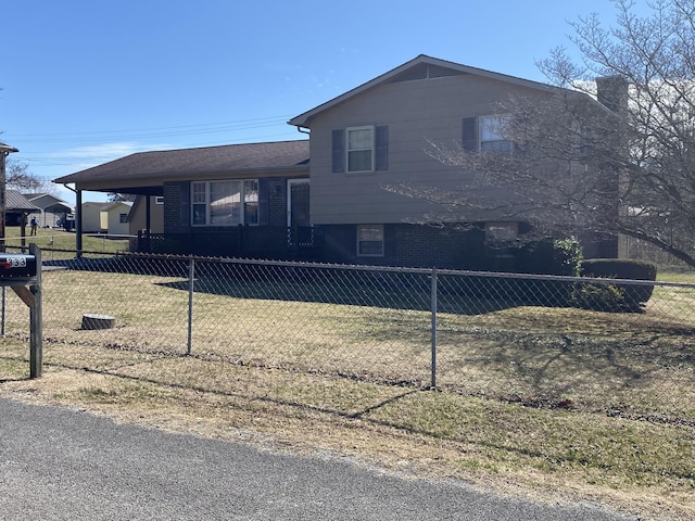 view of front of property with a fenced front yard, brick siding, a carport, and a front lawn