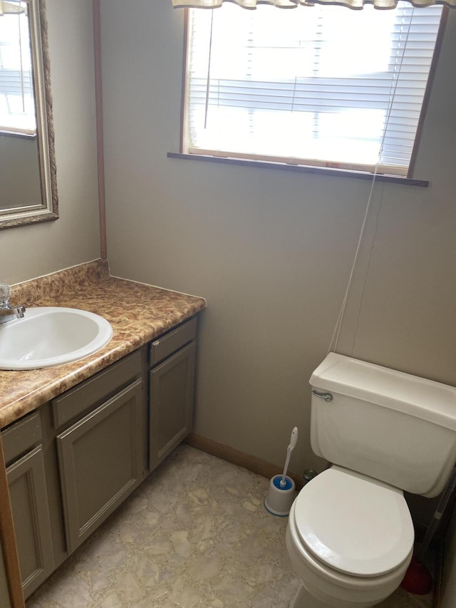 half bath with plenty of natural light, vanity, and toilet