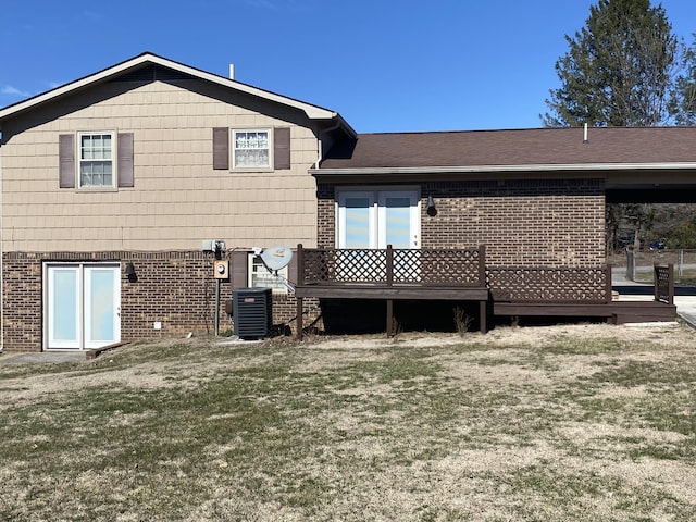 back of property with a lawn, roof with shingles, a wooden deck, central air condition unit, and brick siding