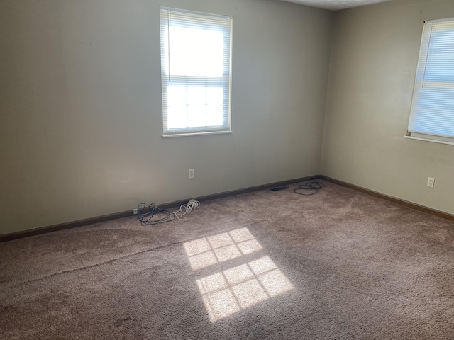 carpeted spare room featuring baseboards