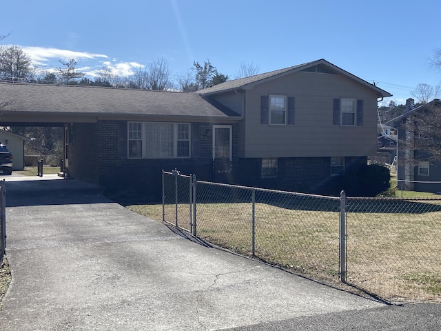 split level home with a fenced front yard, brick siding, and a front lawn