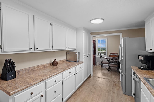 1438 Shannons Little Mtn Rd, Morristown, TN 37814 - kitchen featuring white cabinets, light wood finished floors, light countertops, appliances with stainless steel finishes, and crown molding